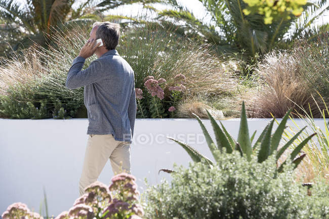 Man talking on a mobile phone in garden — Stock Photo