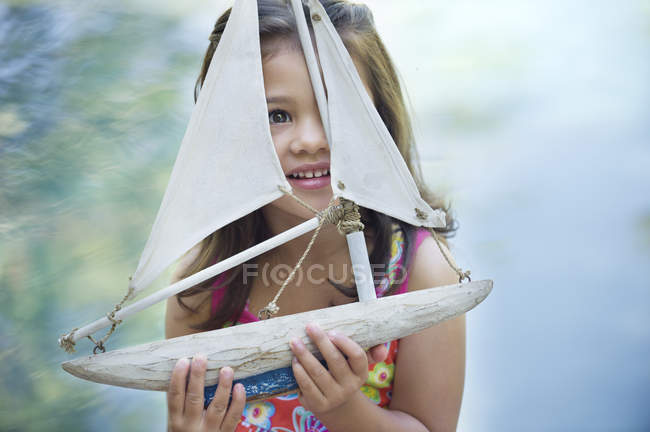 Menina sentada na piscina com modelo de barco — Fotografia de Stock