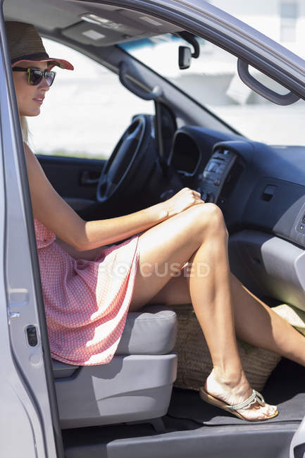 Elegante joven sentada en coche - foto de stock
