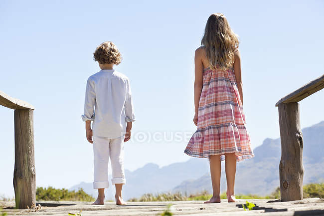 Rear view of siblings standing together at wooden pier — Stock Photo
