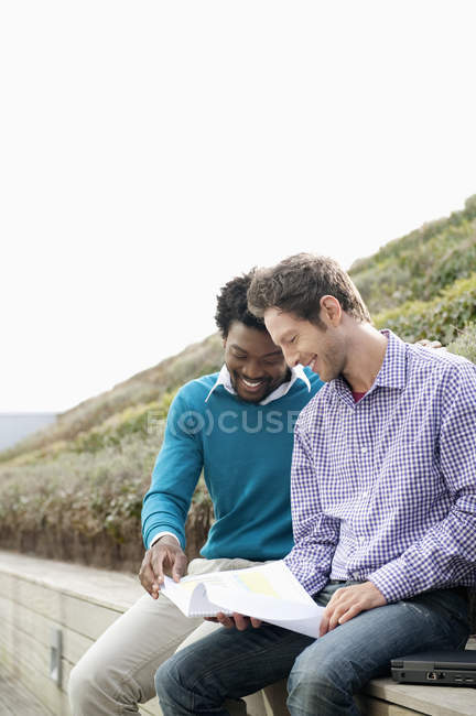 Friends discussing documents on boardwalk in nature — Stock Photo