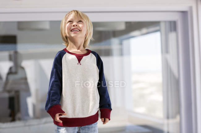 Feliz niño rubio mirando hacia arriba en casa - foto de stock