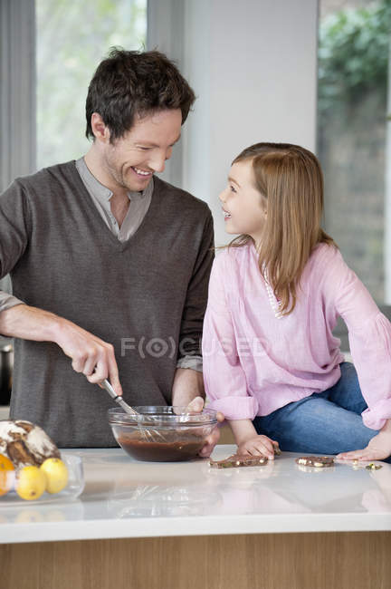 Man stirring a mixture in bowl with daughter — Stock Photo