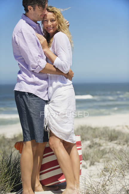 Portrait of happy couple embracing on beach — Stock Photo