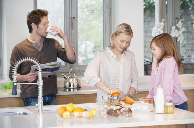Familia preparando el desayuno en la cocina moderna - foto de stock