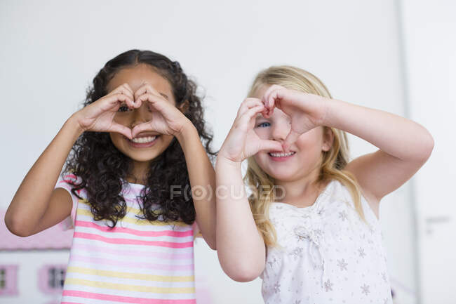 Porträt zweier kleiner Mädchen, die mit den Händen Herzformen herstellen — Stockfoto