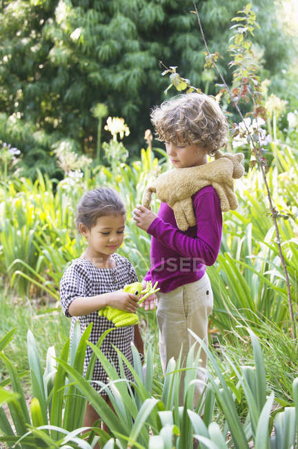 Portrait de petit garçon et fille debout avec des jouets en peluche dans la prairie — Photo de stock