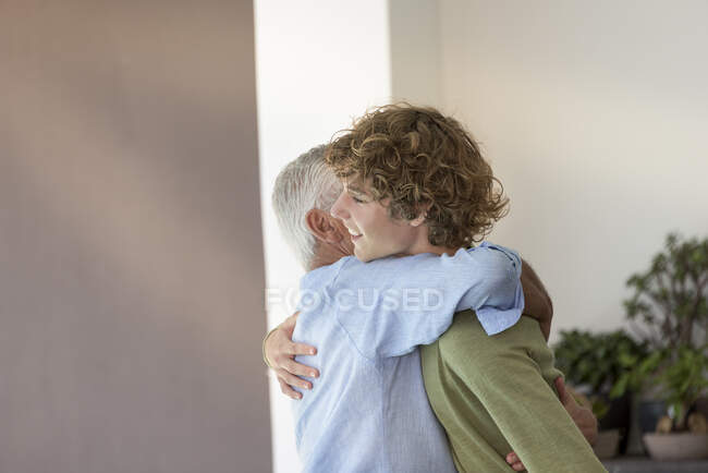 Rapaz adolescente feliz abraçando seu avô — Fotografia de Stock