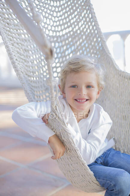 Portrait d'un garçon mignon dans un hamac en plein air souriant à la caméra — Photo de stock