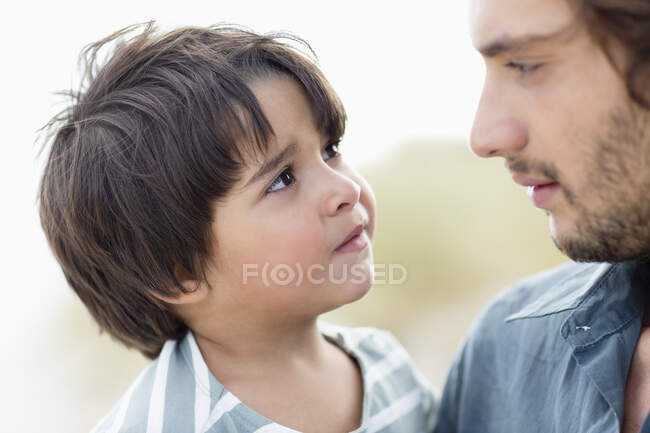Primer plano de un hombre y su hijo mirándose el uno al otro - foto de stock