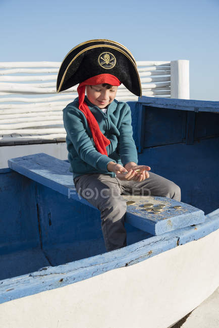 Menino pirata segurando moedas no barco — Fotografia de Stock