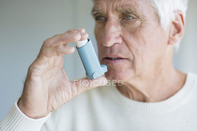 Primer plano del hombre mayor usando inhalador - foto de stock