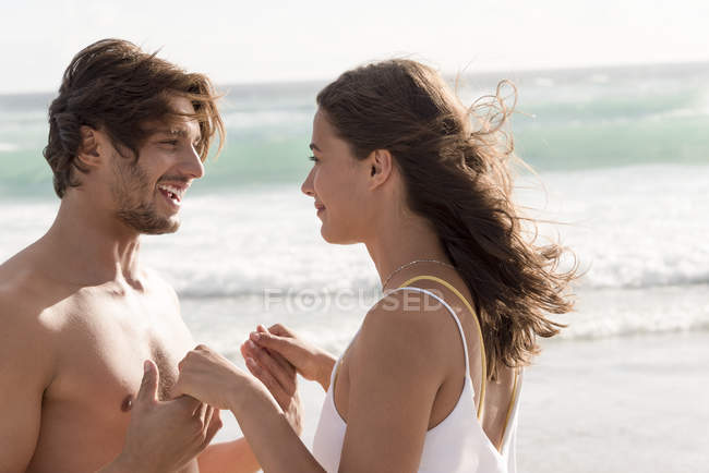 Молода пара романтизує на пляжі з хвилястим морем на фоні — стокове фото
