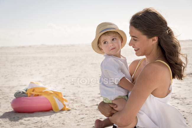 Madre feliz con su pequeño hijo disfrutando en la playa - foto de stock