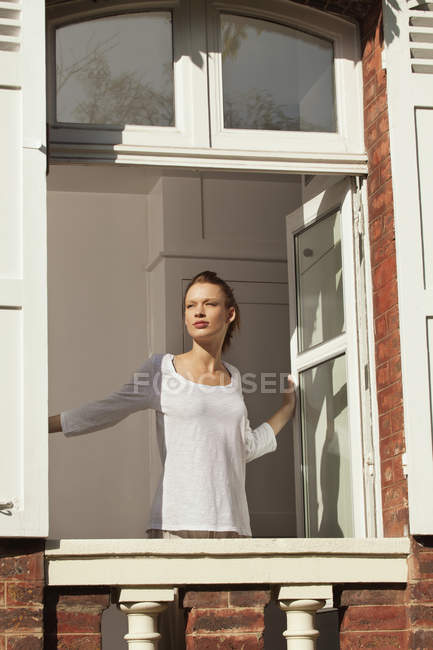 Janela de abertura de mulher jovem no apartamento — Fotografia de Stock