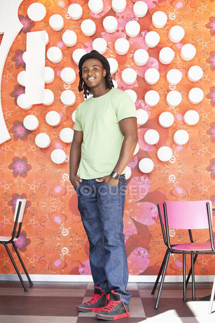 Smiling man in hat with dreadlocks standing at cafe — Stock Photo