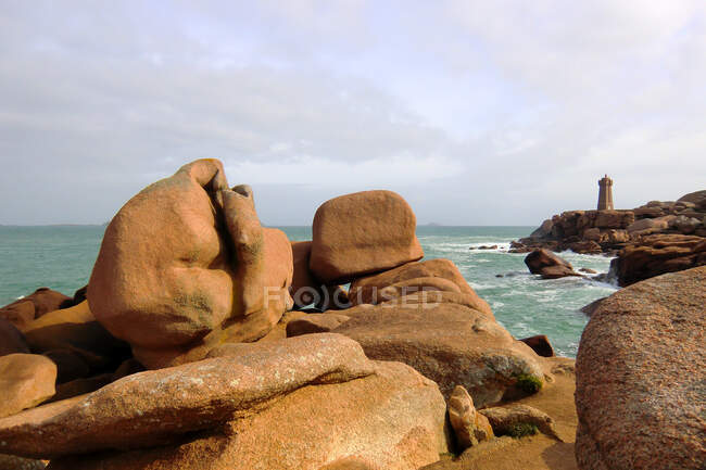 France, North-Western France, Brittany, Ploumanach, pink granite coast and the lighthouse in the background — Stock Photo