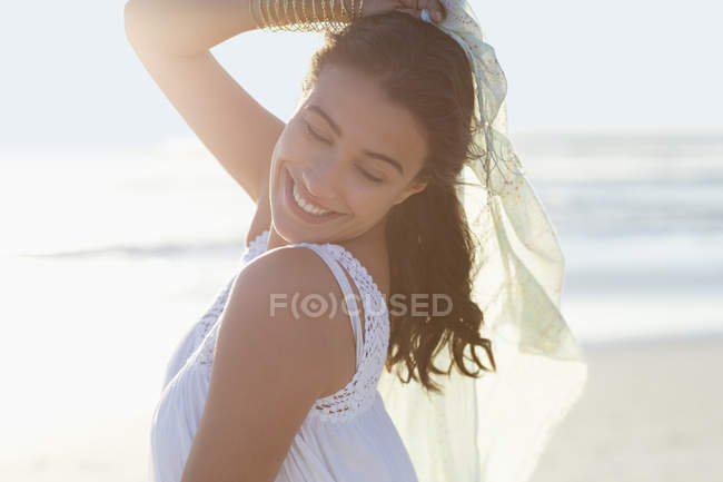 Грайлива молода жінка позує на пляжі з парео — стокове фото
