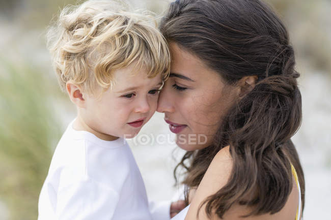 Primo piano di donna che tiene carino figlio bambino triste all'aperto — Foto stock