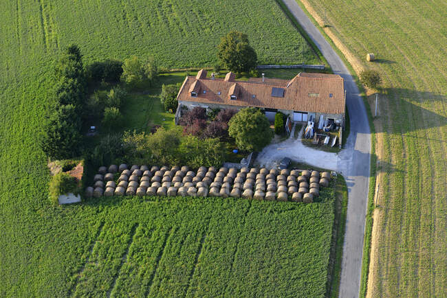 France, Dordogne, aerial view of a house in the middle of a field, surrounded by haystacks — Stock Photo