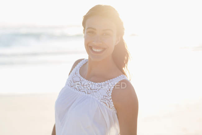 Портрет усміхненої молодої жінки на пляжі на задньому світлі — стокове фото