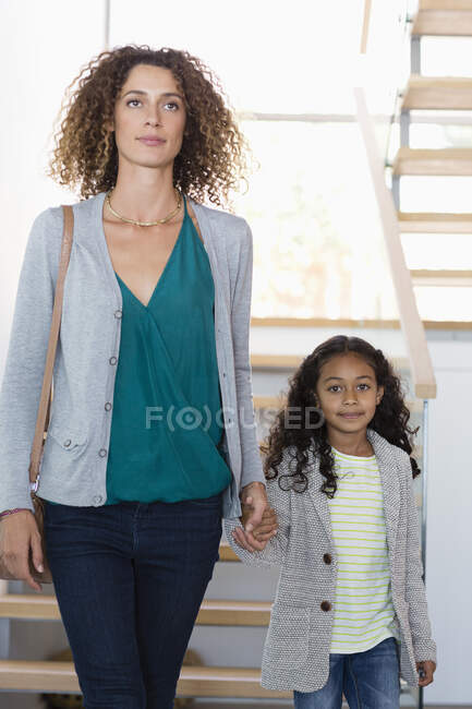 Feliz madre e hija tomados de la mano en la escalera - foto de stock
