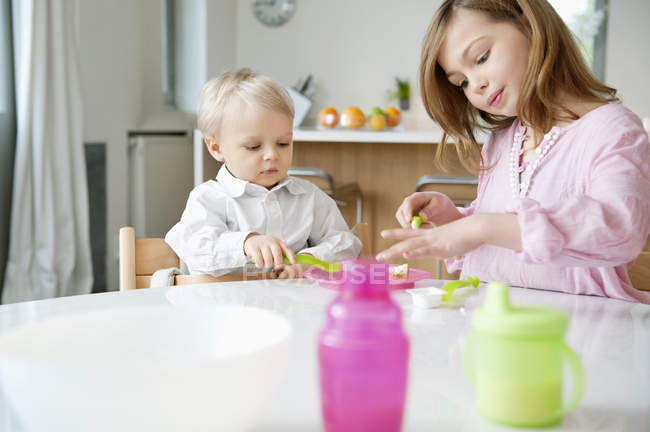 Girl sitting at breakfast table with brother — Stock Photo