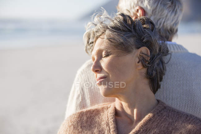 Gros plan d'un couple de personnes âgées attentionné et détendu debout dos à dos sur la plage — Photo de stock