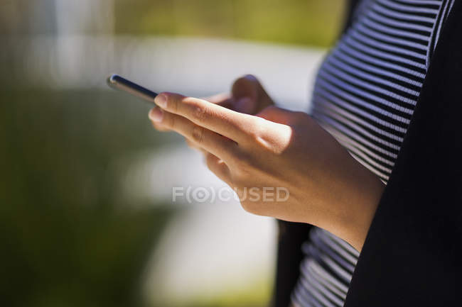 Close-up de mãos femininas usando smartphone ao ar livre — Fotografia de Stock