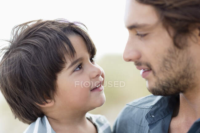 Primer plano de un hombre y su hijo mirándose el uno al otro - foto de stock