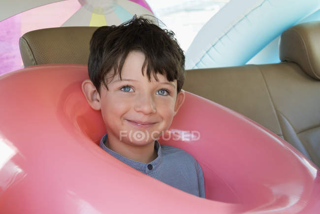 Happy boy in car with rubber ring for vacation — Stock Photo