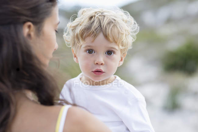 Primo piano di carino bambino in mani di madre all'aperto — Foto stock
