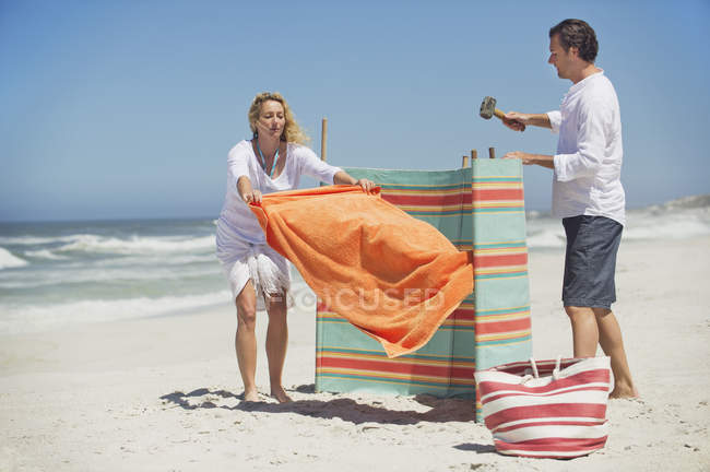 Couple fixing beach screen on sand — Stock Photo