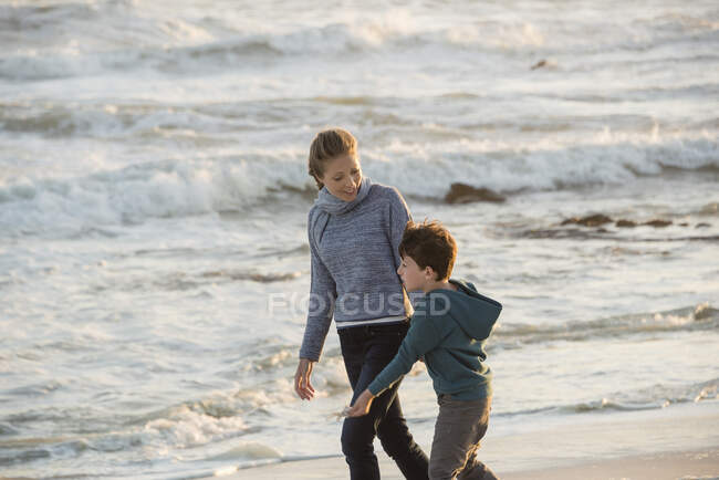 Mãe e filho felizes andando na praia — Fotografia de Stock