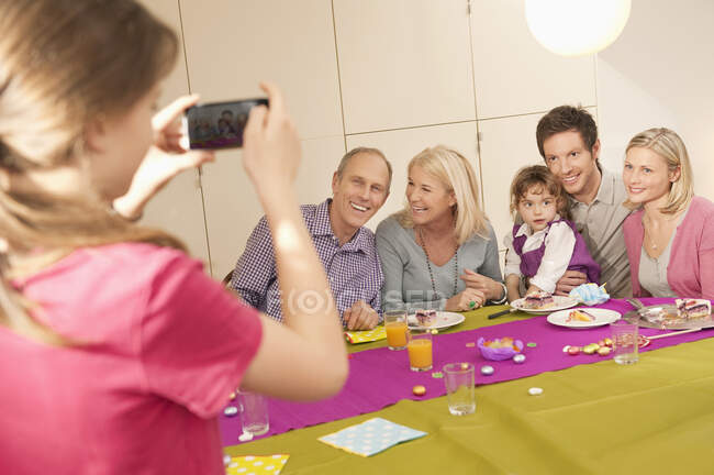 Ragazza scattare una foto della sua famiglia con un telefono fotocamera — Foto stock