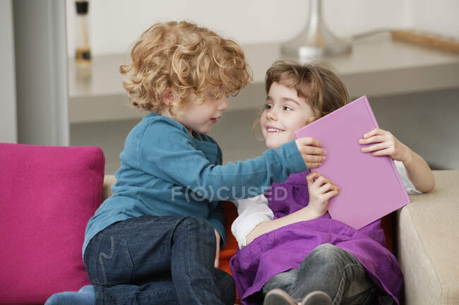 Ragazzo seduto su un divano con sua sorella — Foto stock
