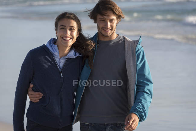 Feliz pareja joven y romántica caminando en la playa - foto de stock