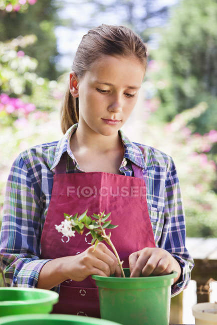 Chica reflexiva en la jardinería delantal al aire libre - foto de stock