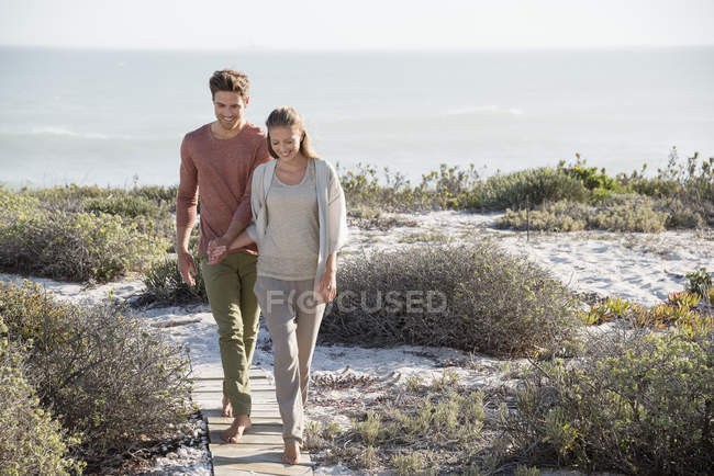 Casal relaxado andando na costa à luz do sol — Fotografia de Stock