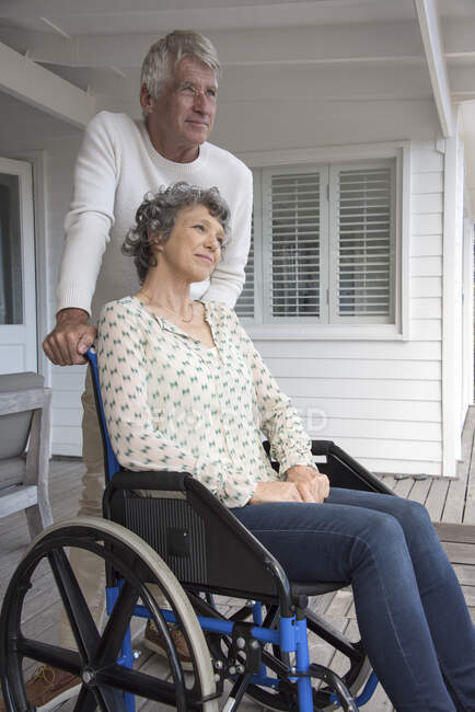 Senior homme aider sa femme en fauteuil roulant sur le porche — Photo de stock