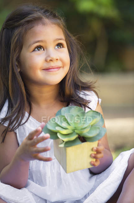 Menina bonito segurando vaso planta e olhando para cima — Fotografia de Stock