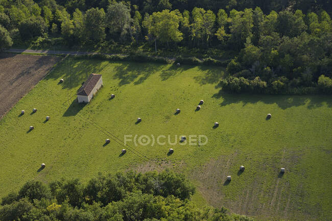 Франция, Дордонь, воздушный вид на зеленое поле и стог сена между двумя лесами. Дом слева. — стоковое фото