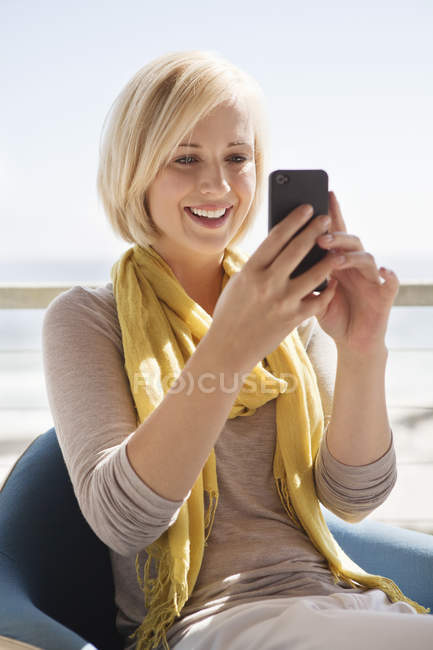 Улыбающаяся женщина с мобильным телефоном на улице — стоковое фото