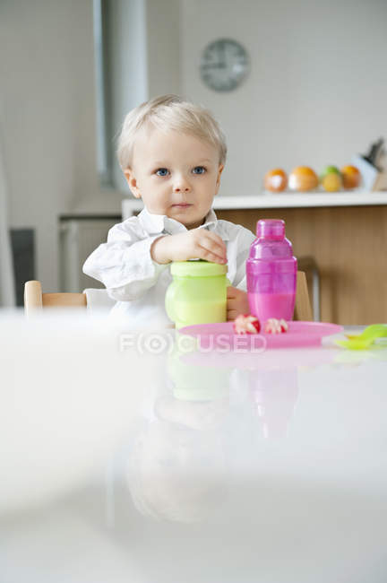 Niño con el pelo rubio sentado en una mesa de comedor - foto de stock