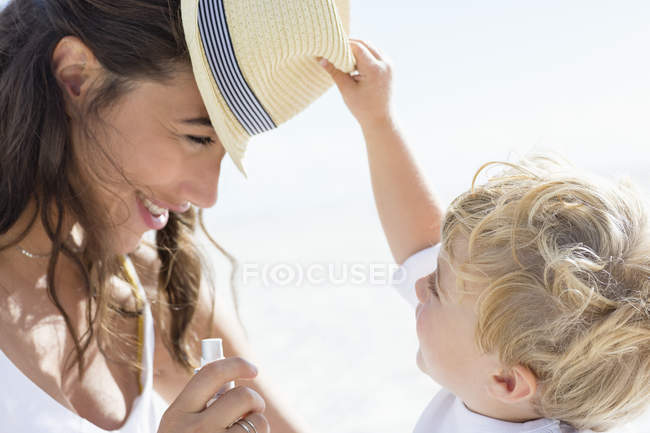 Дитячий хлопчик грає з матір'ю капелюхом на пляжі — стокове фото