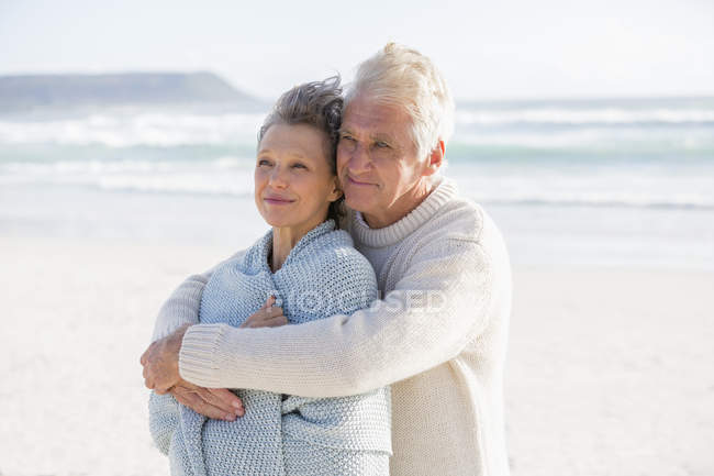 Felice uomo abbracciare moglie da dietro sulla spiaggia — Foto stock