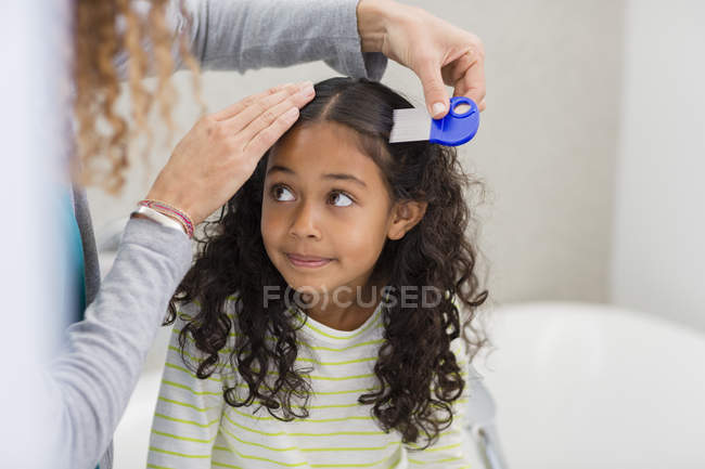 Mãe usando pente de piolhos no cabelo da filha — Fotografia de Stock