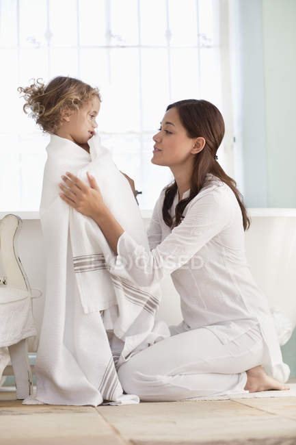 Donna avvolgente figlia in asciugamano dopo il bagno — Foto stock
