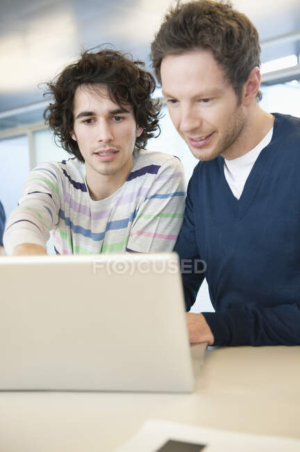 Empresarios usando un portátil en una oficina - foto de stock