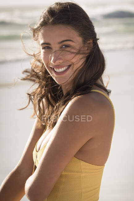 Portrait of happy young woman standing on beach — Stock Photo